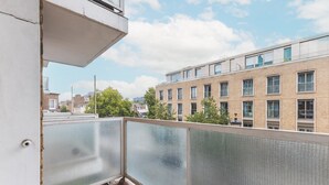 Ein Balkon mit Blick auf ein Backsteingebäude und Bäume.