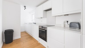 Eine moderne Küche mit weißen Schränken, einem schwarzen Backofen, einem Toaster und einem Mülleimer.