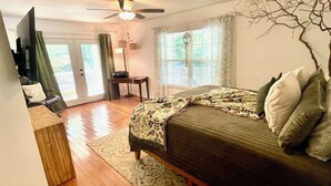 A bedroom with a bed, a desk, a television, and a ceiling fan. - Etowah Valley Ranch - Peaceful, private, and serene!  CLose to everything! (Dahlonega)