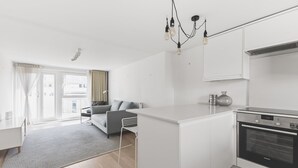 A modern kitchen with a built-in oven, a dining area with a white table, and a grey sofa. - Cozy Belgravia Base - Walk to Victoria/Sloane (London)