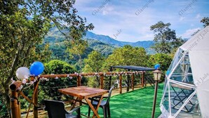 An outdoor seating area with tables and chairs, a pergola with flowers, and a view of mountains. - Glamping el Jade (San Francisco)