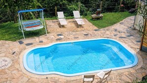 A swimming pool with a stone deck, surrounded by lounge chairs and a swing chair. - Glamping el Jade (San Francisco)
