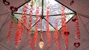 A tent with a geometric ceiling structure, adorned with hanging red flowers and heart-shaped decorations. - Glamping el Jade (San Francisco)