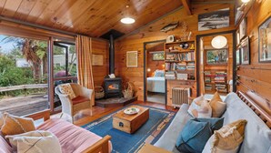 Ein gemütliches Blockhaus-Interieur mit Holzausstattung, Kamin, Bücherregal und einer komfortablen Sitzecke.