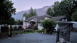 A house with a gated driveway, a covered porch, and a mountain backdrop.