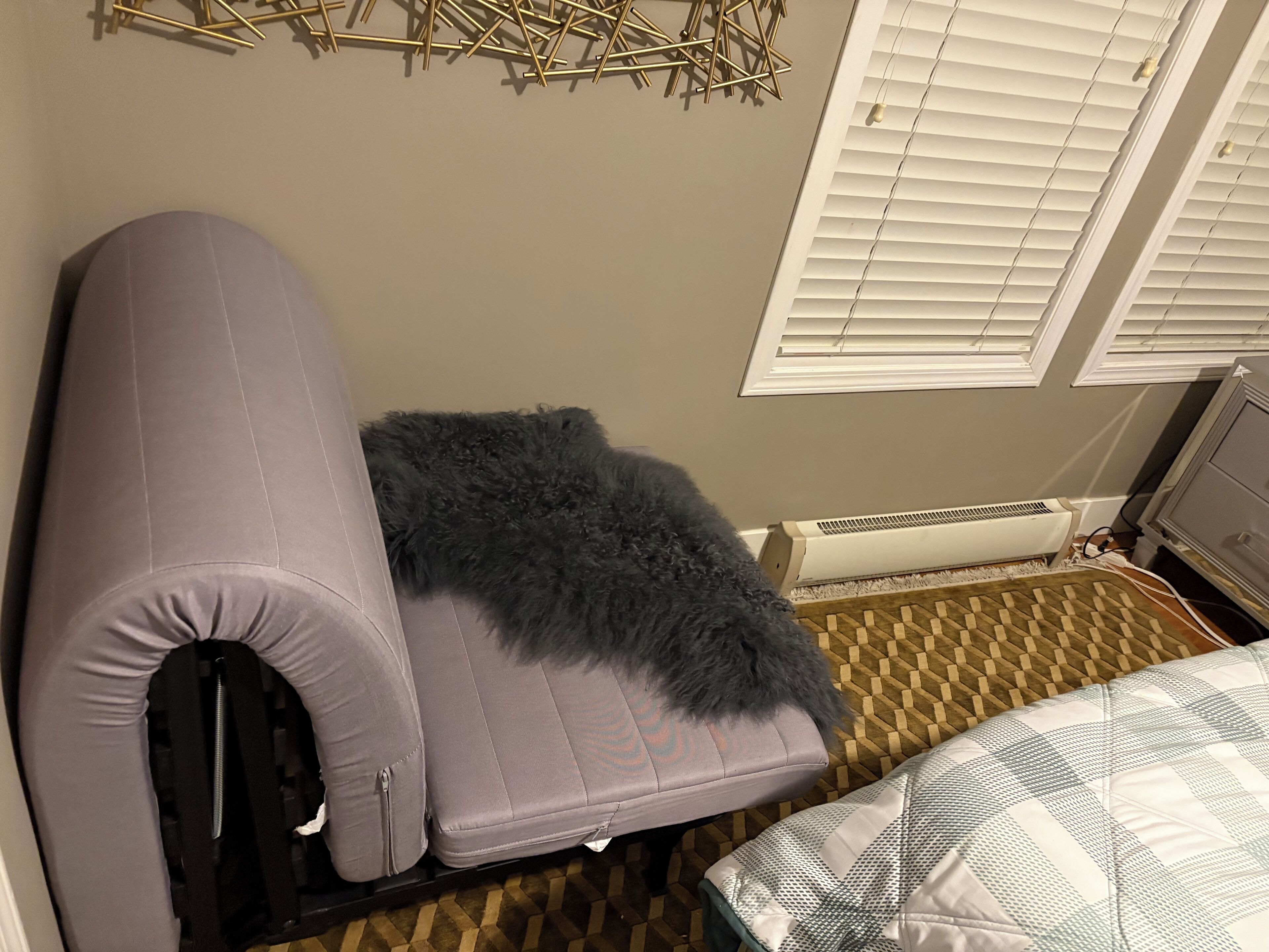 Una habitación pequeña con cama, una mesita y un calentador.