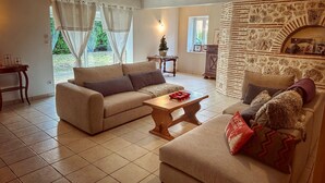 A cozy living room with a stone fireplace, a sofa set, and a dining table. - Maison de campagne à Aiguillon, Garden, Terrace, Game room, No pets allowed (Aiguillon)