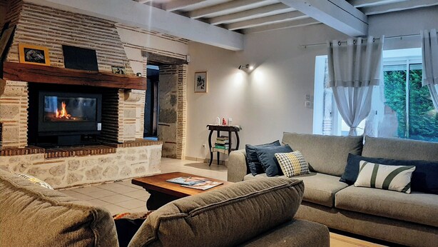 A cozy living room with a stone fireplace, a comfortable sofa, and a television. - Maison de campagne à Aiguillon, Garden, Terrace, Game room, No pets allowed (Aiguillon)