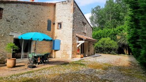 A stone building with a patio area, outdoor seating, and a covered table. - Maison de campagne à Aiguillon, Garden, Terrace, Game room, No pets allowed (Aiguillon)