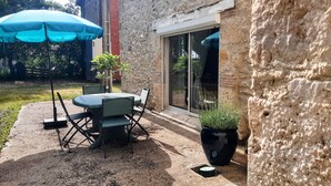 An outdoor patio with a table and chairs, a blue umbrella, and a potted plant. - Maison de campagne à Aiguillon, Garden, Terrace, Game room, No pets allowed (Aiguillon)