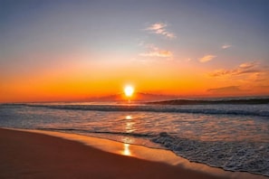 Una platja amb el sol ponent-se sobre l'oceà.