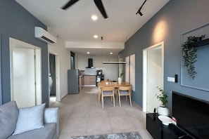 Una sala de estar moderna con un sofá, una mesa de comedor con sillas, una chimenea y una cocina al fondo.