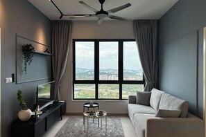 Un salon moderne avec un canapé, un téléviseur, une petite table et un ventilateur de plafond.