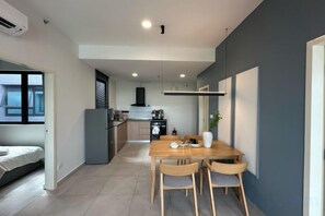 Un espace de vie compact comprenant un coin repas, une kitchenette et un lit.
