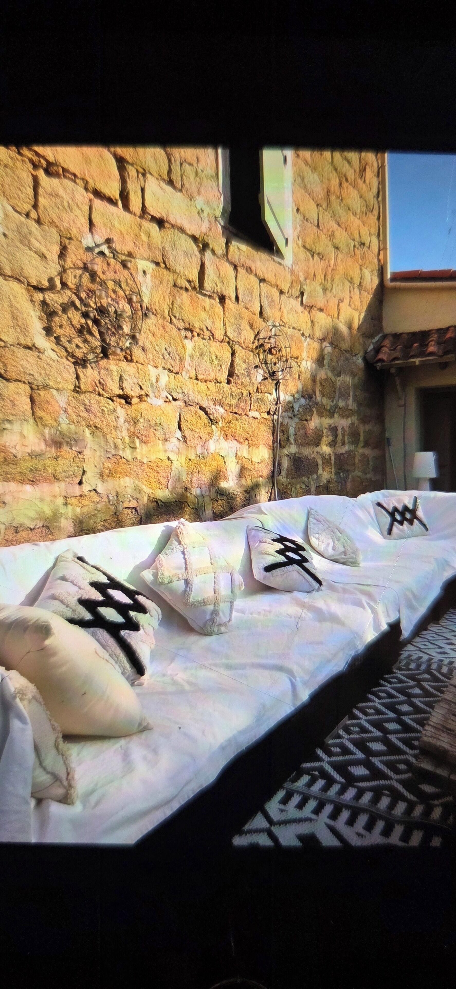 A bed with pillows, a brick wall, and a window in a room.