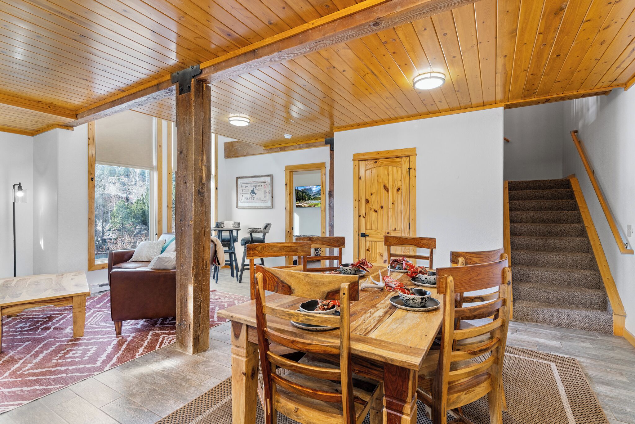 A wooden dining table with chairs, a bench, and a staircase.