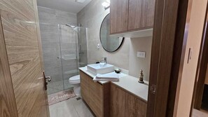 Une salle de bain avec une douche à parois de verre, des toilettes et un meuble-lavabo avec un miroir.