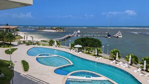Ein Resort mit einem großen, gebogenen Pool, einer Marina mit Booten und einem Strandbereich.
