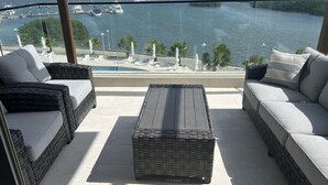 Ein Balkon mit Korbmöbeln, Blick auf das Meer und Boote.