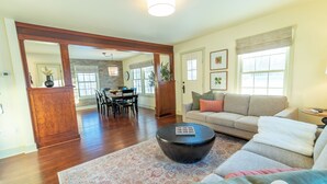 A spacious living room with a large sofa, a coffee table, and a dining area in the background. - Quarter 54 (Palmer)