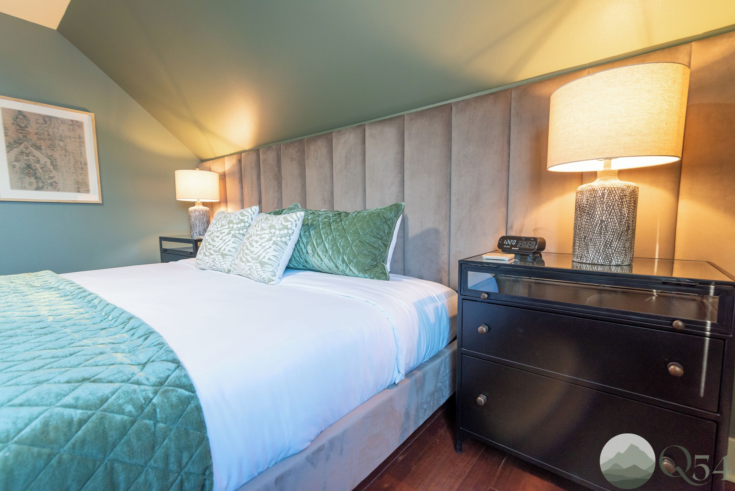 Une chambre à coucher avec un lit, deux lampes de chevet, une table de chevet et une lampe fixée au mur.