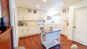 A kitchen with white cabinets, a central island, and wooden flooring. - Quarter 54 (Palmer)