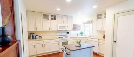 A kitchen with white cabinets, a central island, and wooden flooring.