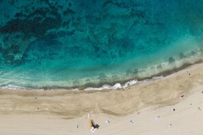 An aerial view of a beach with clear turquoise water, sandy shore, and people sunbathing. - Home2Book Apartment with Pool Playa las Américas (Playa de la Américas)