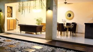 A modern interior with a sofa, dining table, and chairs, a Buddha statue, and a decorative mirror. - VIlla Avi (Bali)