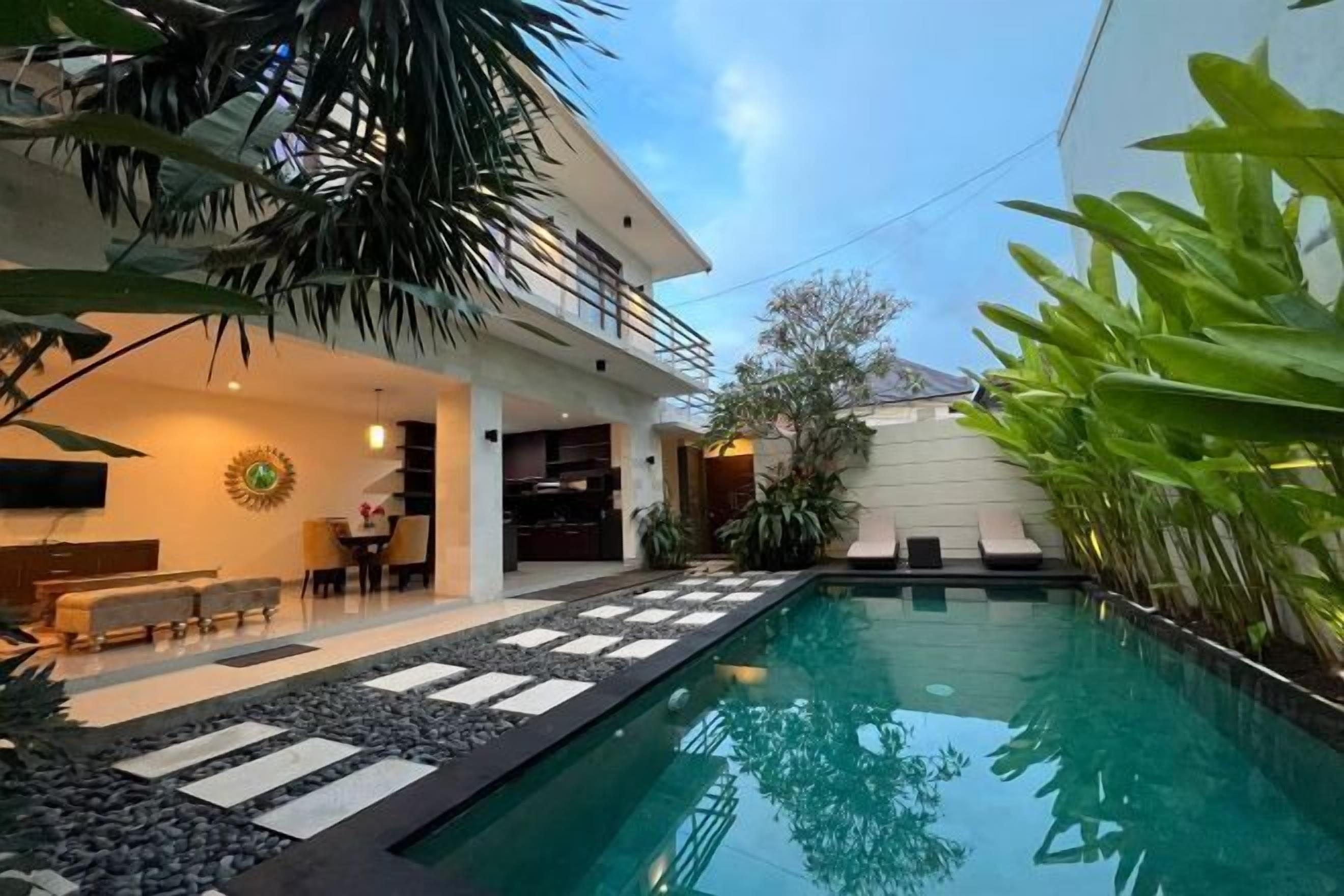 A modern house with a swimming pool, outdoor seating, and lush greenery.