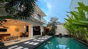 A modern house with a swimming pool, outdoor seating, and lush greenery. - VIlla Avi (Bali)