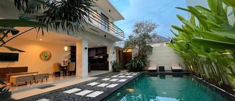 A modern house with a swimming pool, outdoor seating, and lush greenery.