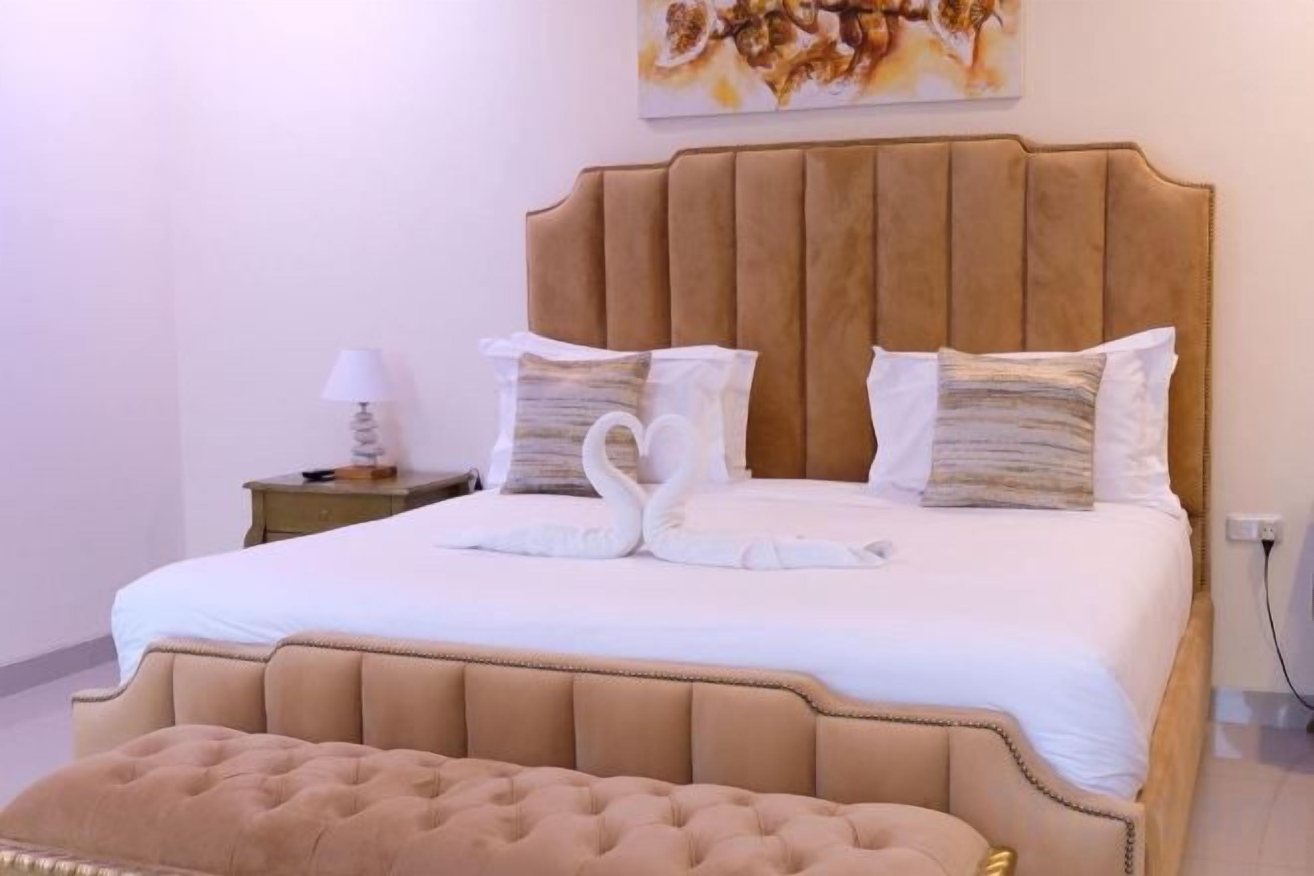 Een bed met hoofdeinde, kussens en een zwaan-vormige kussensamenstelling.