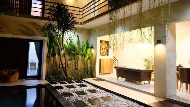 A multi-level interior with a central staircase, a Buddha statue, and a seating area. - VIlla Avi (Bali)