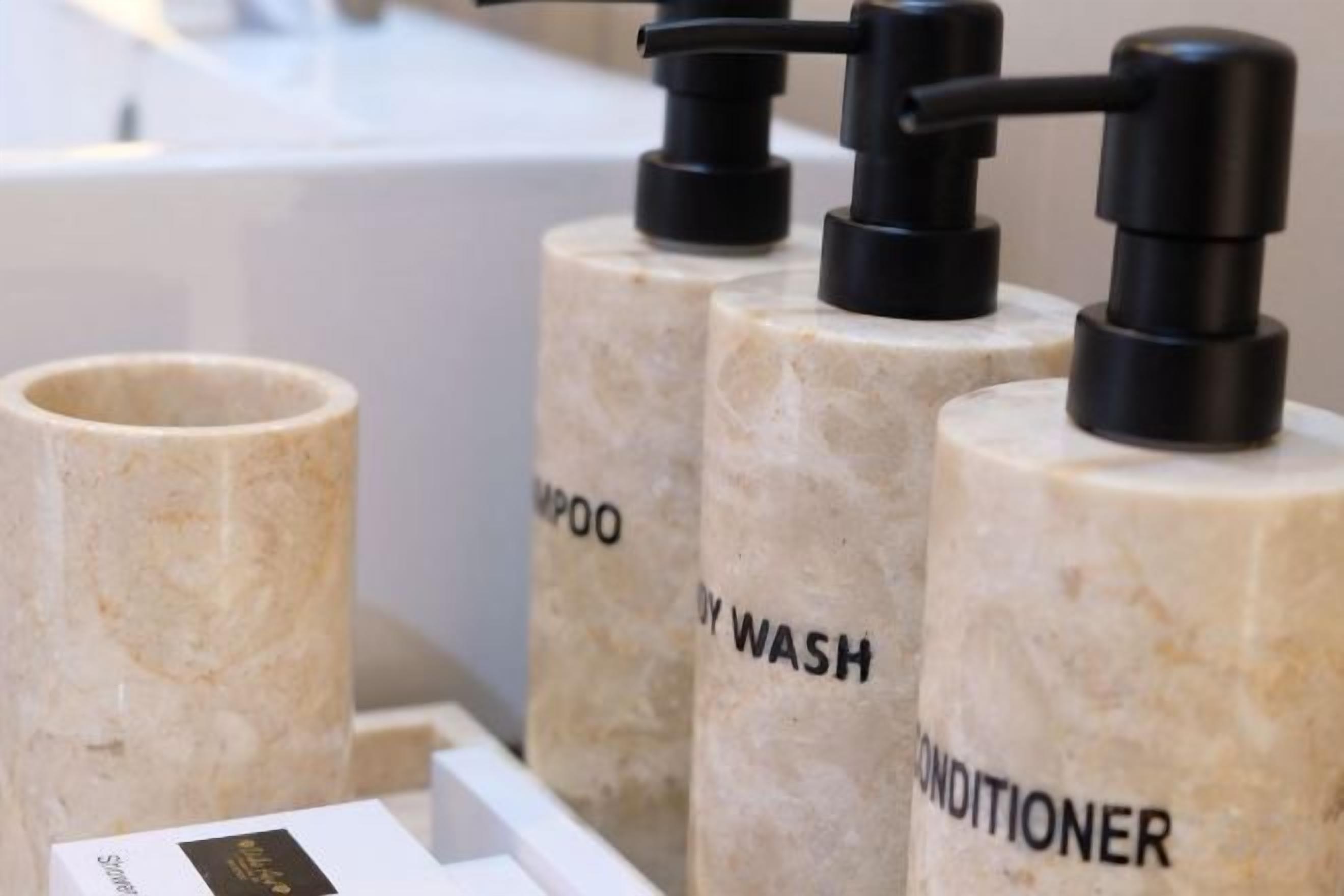 A bathroom with three cylindrical dispensers labeled 'SHAMPOO,' 'WASH,' and 'CONDITIONER.'