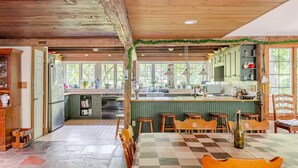 A rustic kitchen with wooden beams, a large island with stools, and a view of the outdoors through large windows. - Country home in beautiful Bucks County (Hatfield)
