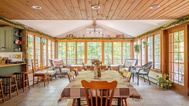 A dining area with a long table, chairs, and a kitchen area with a counter and shelves. - Country home in beautiful Bucks County (Hatfield)