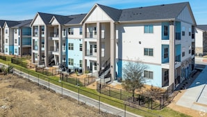 A row of modern multi-story apartment buildings with balconies, a central courtyard, and a well-maintained lawn. - Landing Apartments Austin - Lockhart (Lockhart)