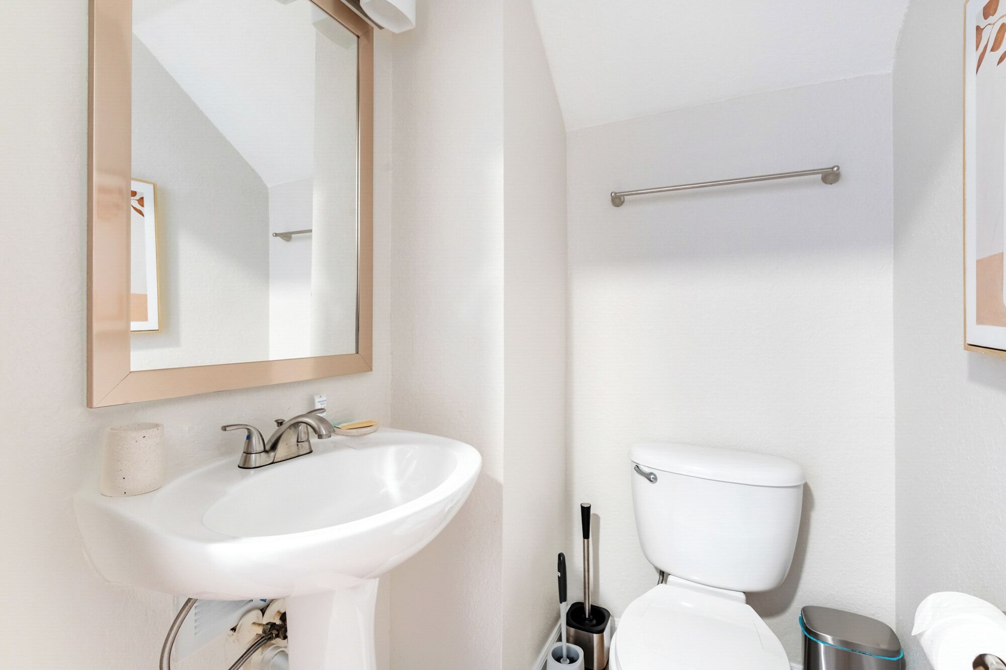Un baño con lavamanos blanco, un espejo, inodoro y zona de ducha.