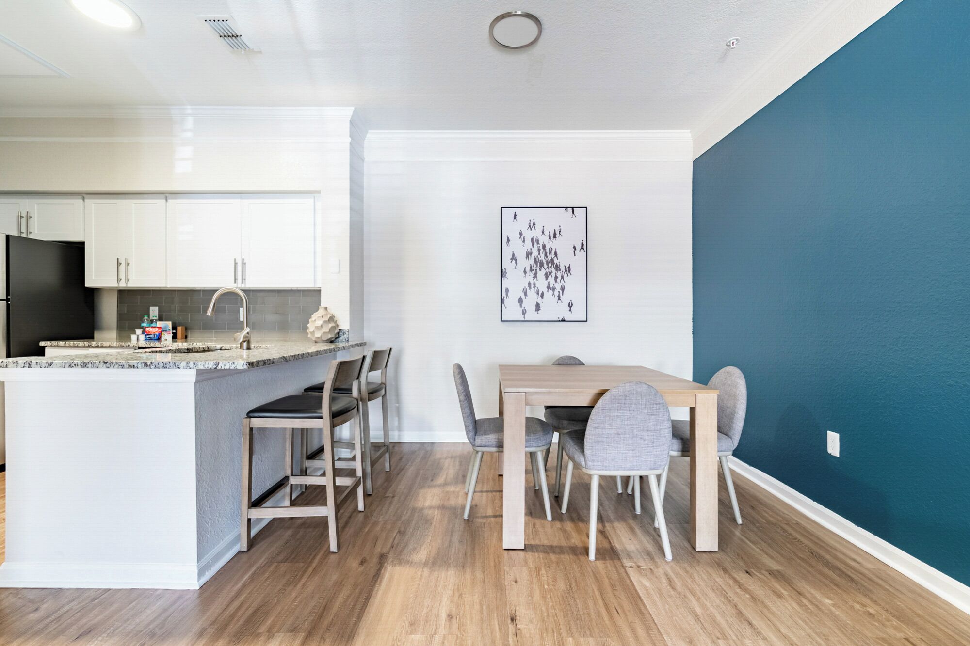 A modern kitchen with white cabinets, a black refrigerator, and a granite countertop.