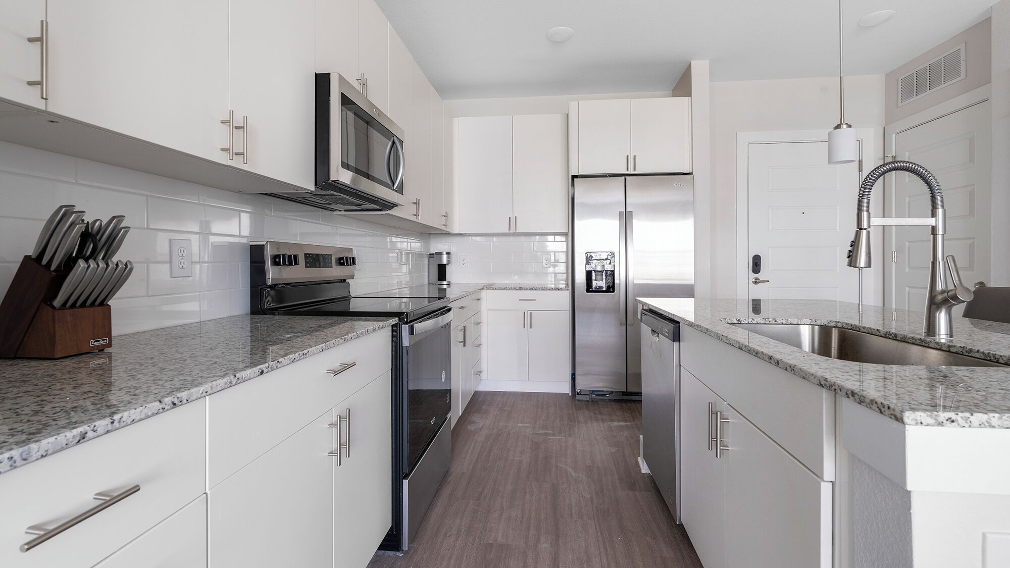 Una cocina moderna con armarios blancos, electrodomésticos de acero inoxidable y encimera de granito.