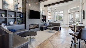 A modern living room with a fireplace, a large flat-screen TV, and a seating area with a sofa and chairs. - Landing Apartments Charleston - Summerville (Summerville)