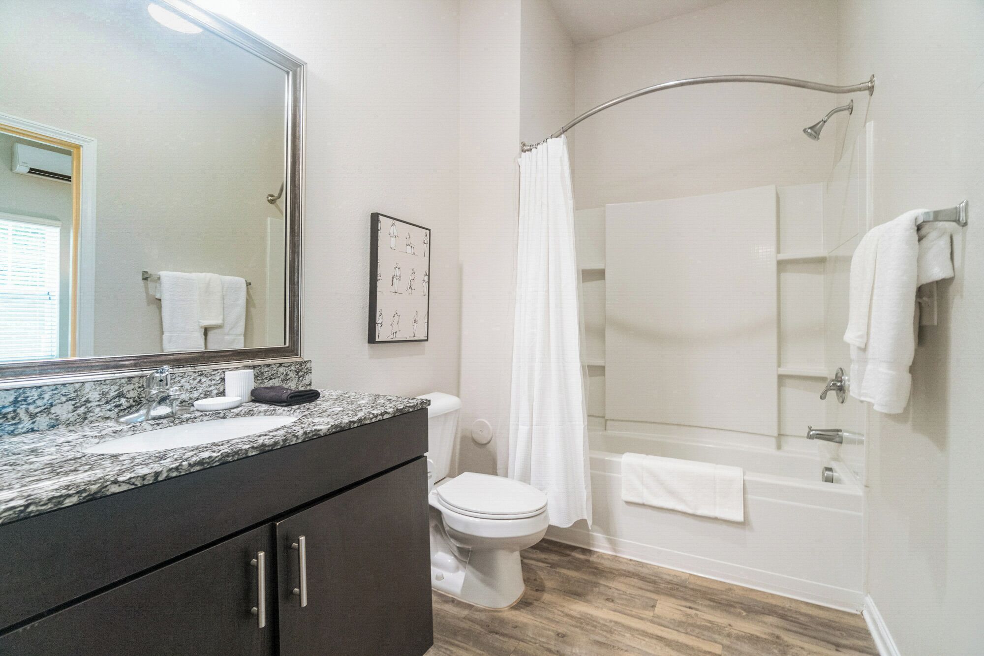 A bathroom with a marble countertop, a toilet, a shower with a glass door, and a large mirror.