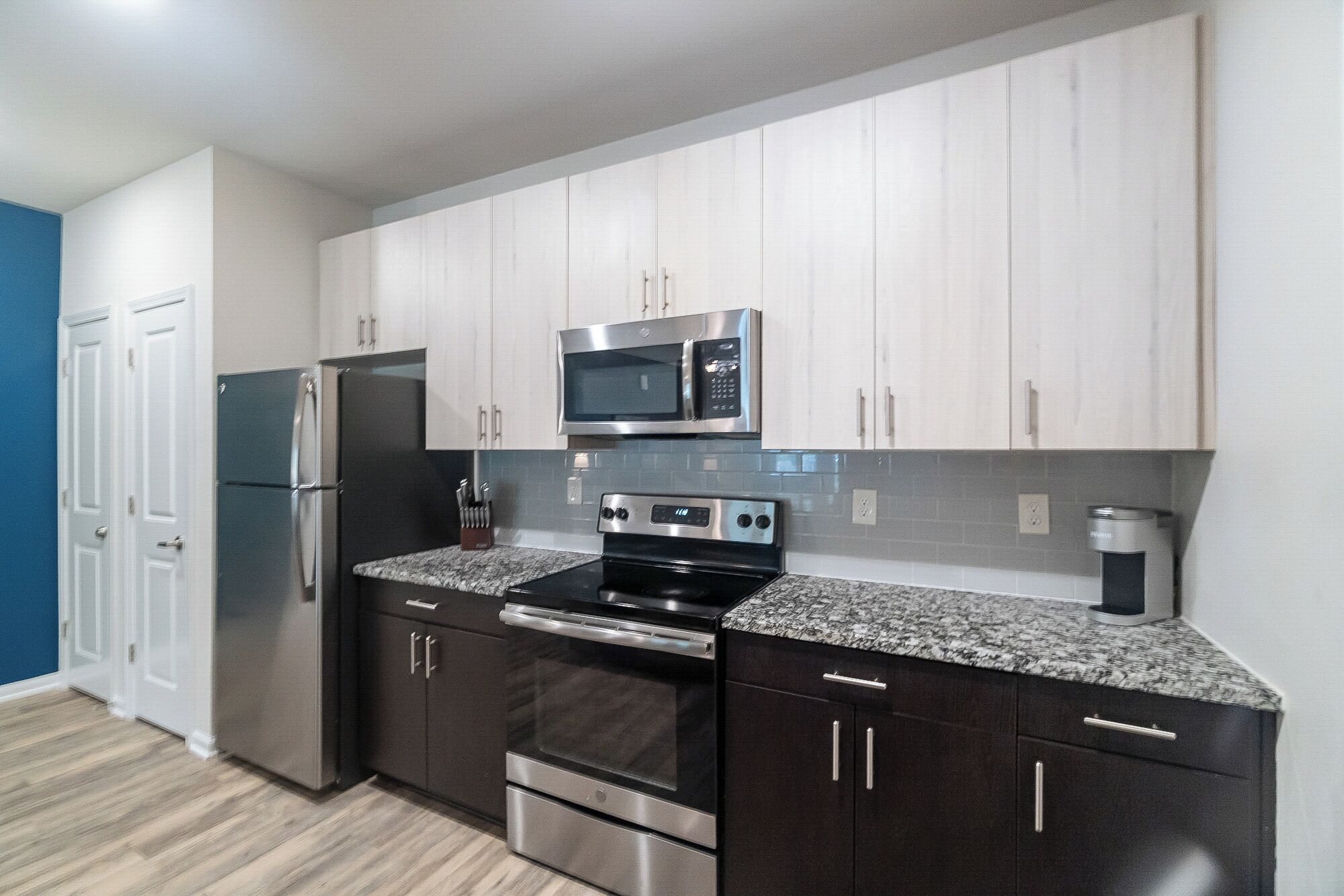 A modern kitchen with stainless steel appliances, dark cabinetry, and a granite countertop.
