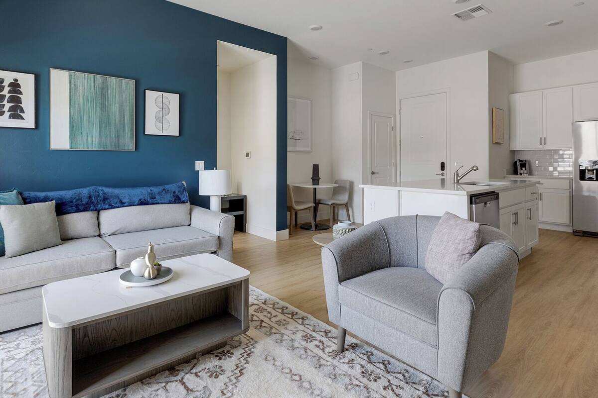 Un salon moderne avec un canapé, un fauteuil, une table basse et des œuvres d’art accrochées au mur.