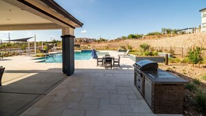 Un patio couvert avec une piscine, un espace salon extérieur et un coin barbecue.