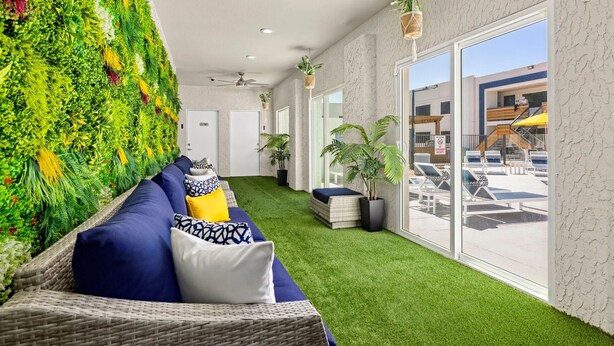 Un intérieur moderne avec un mur vert, un canapé bleu et une vue sur l’extérieur.