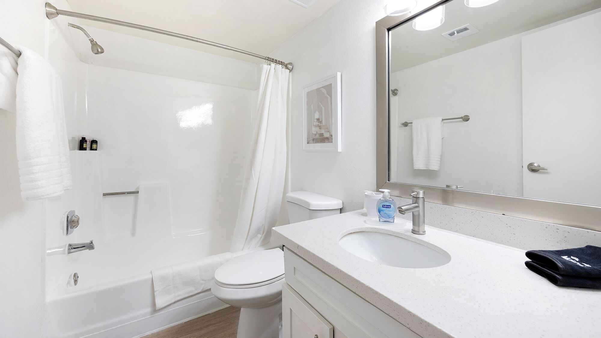 A modern bathroom with a glass-enclosed shower, a white toilet, a sink with a mirror, and a towel rack.