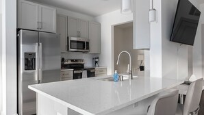Una cocina moderna con electrodomésticos de acero inoxidable, microondas integrado y una isla grande con pileta.