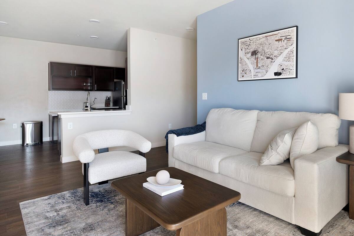 A modern living room with a sofa, a coffee table, a side table with a lamp, and a potted plant.